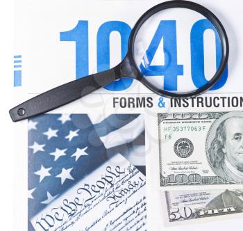 Tax form booklet 1040 with magnifying glass and money on white background