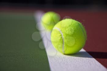 Two tennis balls on baseline of brand new tennis court