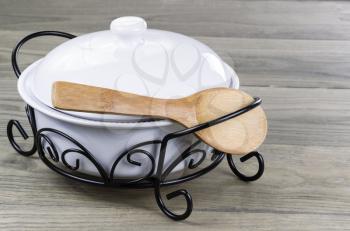 Traditional serving pot with wooden spoon on Stressed wooden table