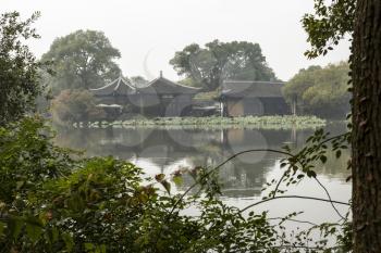 Large temple seen through trees on other side of West Lake in Hangzhou China on Hazy Day