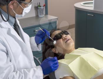 Horizontal photo of a male dentist preparing to work on woman patient