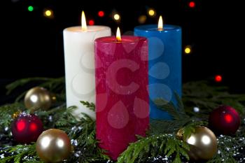 Colorful candles in white, red, blue in seasonal setting on black background