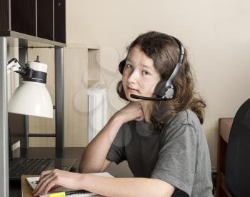 Young girl preparing to do homework with headset on while sitting at her desk