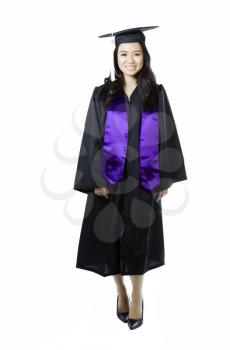 Vertical photo of young adult woman, dress in graduation gown and cap, on a white background