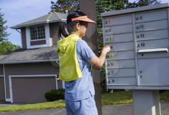 Horizontal photo of a mature woman checking her mailbox with a Northwest American home in the background 