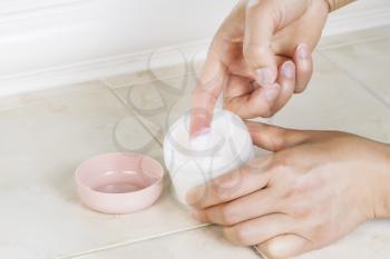 Close up horizontal photo of female hands dipping index finger into cosmetic cream 
