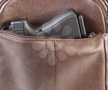 Photo of modern personal weapon in woman brown leather handbag
