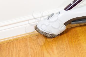 Horizontal photo of vacuum cleaner brush extension cleaning floor and trim work 