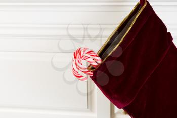 Horizontal photo of Christmas stocking hanging from fireplace mantle with real candy canes hanging outside