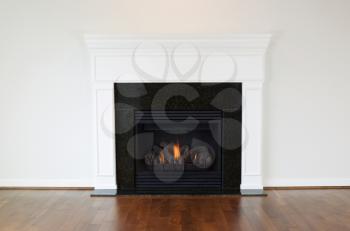 Horizontal photo of a natural gas fireplace with a white mantle and cherry wood floors 