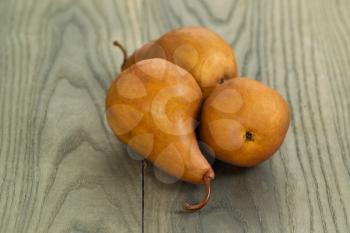 Horizontal photo of three brown pears on aged wood