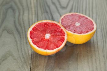 Horizontal photo of sliced ruby red grapefruit on aged wood