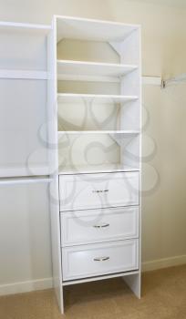 Vertical photo of modern white shelf inside of master bedroom closet residing on carpet