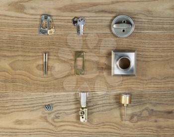 Overhead view of residential home door lock parts placed on rustic wooden boards. 