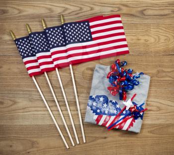 Overhead view of United States of America flags, ribbons, t-shirt and pinwheels positioned on rustic wooden boards
