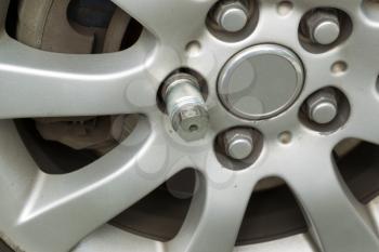 Closeup horizontal photo of locking wheel nut key on car wheel rim  