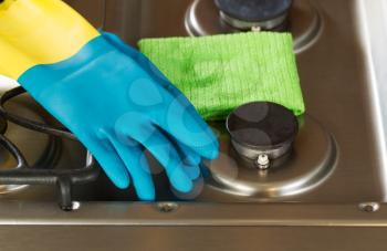 Closeup horizontal image of rubber gloves and microfiber rag on top of stove top range 