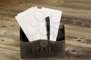 Front view of an old metal mailbox filled with white envelopes and letter opener on rustic wooded boards