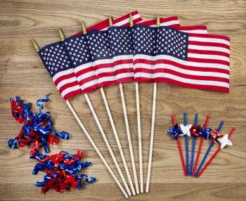 Overhead view of United States of America flags, ribbons and pinwheels positioned on rustic wooden boards.  