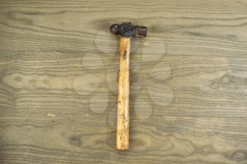 Horizontal photo of an old ball peen hammer on aged wood