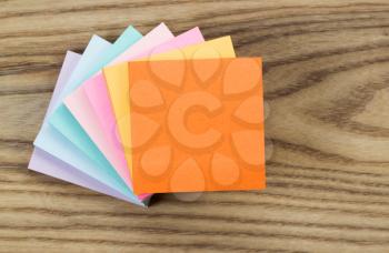 Overhead view of a stack of multi-color paper sticky notes placed on rustic wood.  
