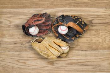 Horizontal top view photo of old baseball gloves and balls on top of faded wood
