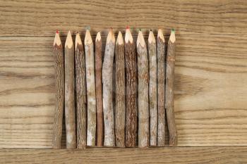 Overhead view of old pencils with tree bark on rustic wood