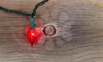 Top view of a single red Christmas light on rustic wood 