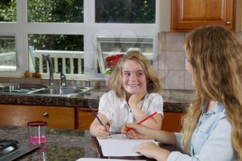 Front view of sisters doing their homework in the kitchen