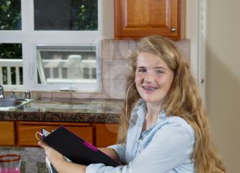 Front view, looking forward, of teenage girl doing her homework while in the kitchen