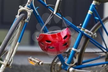 Closeup image of used red bicycle helmet with home in background 
