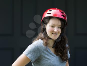 Closeup image of teenage girl, looking forward with helmet on, with home front door in background