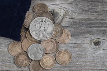 Close up view of a bag of United States vintage coins spilling out onto rustic wood