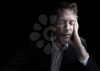 Portrait of businessman closing eyes while working late at night on black background with copy space 