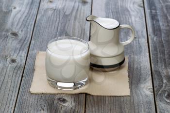 Fresh glass of milk and pourer on rustic wood

