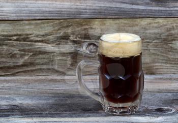 Horizontal image of a glass stein filled with dark draft stout beer on rustic wood