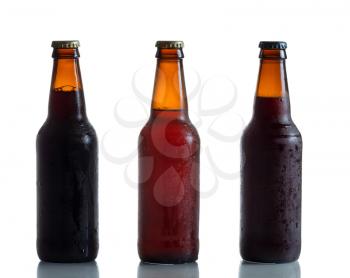 Cold unopened dark and amber beer bottles on white with reflection

