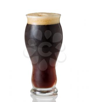 Tall shapely glass filled with dark European beer on white with reflection
