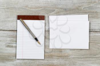 Top view of business envelope and writing pen with notepad on rustic white wooden desktop 