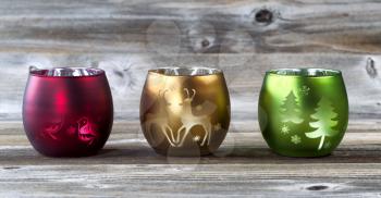 Bright holiday candle cup holders on rustic wood 