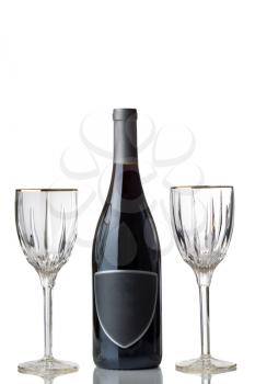 Vertical image of an unopened bottle of red wine, with empty glasses, isolated over white background with reflection