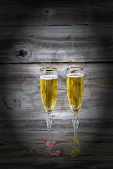 Vertical image of Golden champagne in elegant glasses on rustic wood with vignette