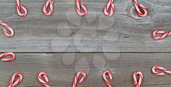 Top view close up of candy canes forming border on rustic wooden boards 
