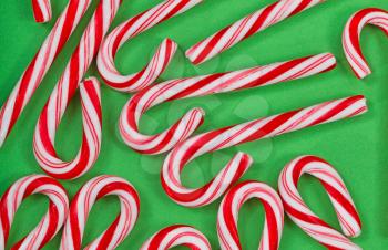 Top view close up of seasonal candy canes placed on green paper 