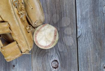 Partial old worn glove and used baseball on rustic wood 