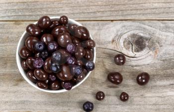 Overhead shot of dark chocolate and blueberries in white bowl on rustic wood