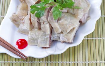 Close up image of Chinese cooked chicken, parsley, cherry and chopsticks on white plate with natural bamboo place mat background 