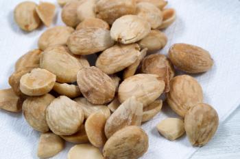 Close up view of a pile of salted almonds on white cloth napkin. Focus front middle of pile. 
