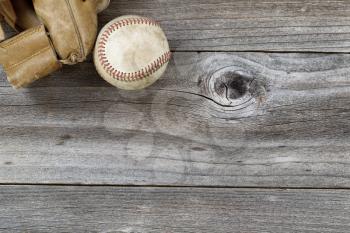 Horizontal top view angle of old baseball and weathered leather mitt on rustic wood 