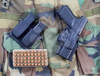 Top view angled shot of United States military uniform, weapon, clips and box of ammo in horizontal layout.  